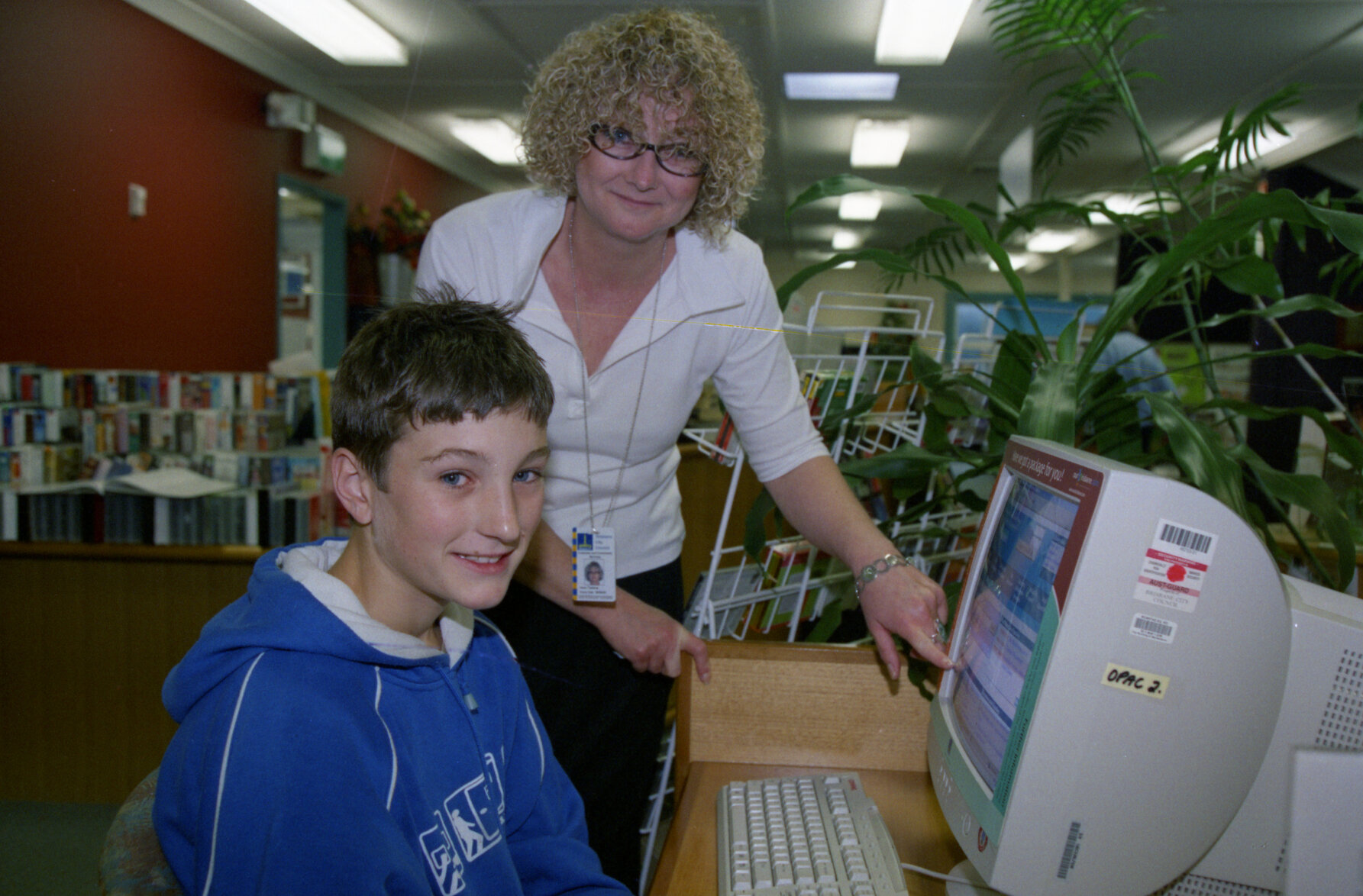 Librarian showing customer digital library catalogue, Stones Corner Library - 2003