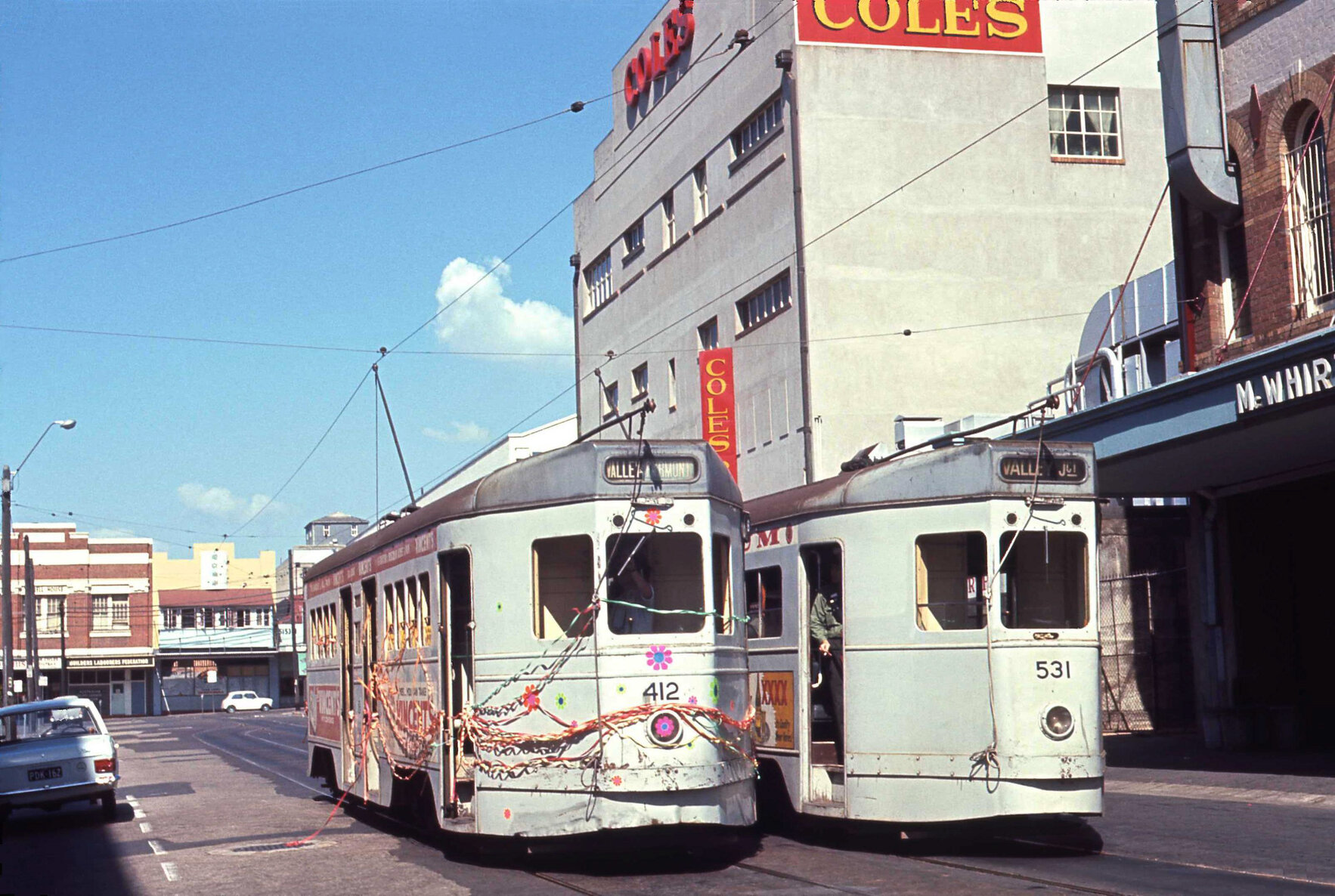Tram No. 412 painted with flowers and covered with ribbons with No. 531 on Warner Street, Fortitude Valley - 1969