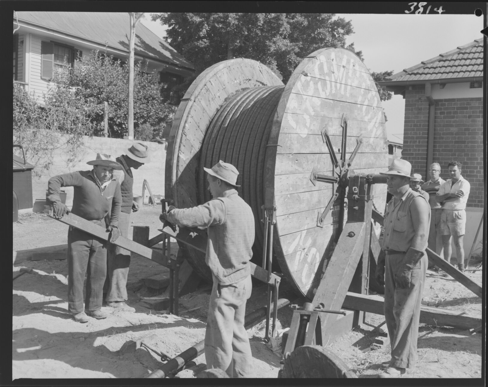 Workmen unspooling electrical cable for line from Kangaroo Point to New Farm - 1953