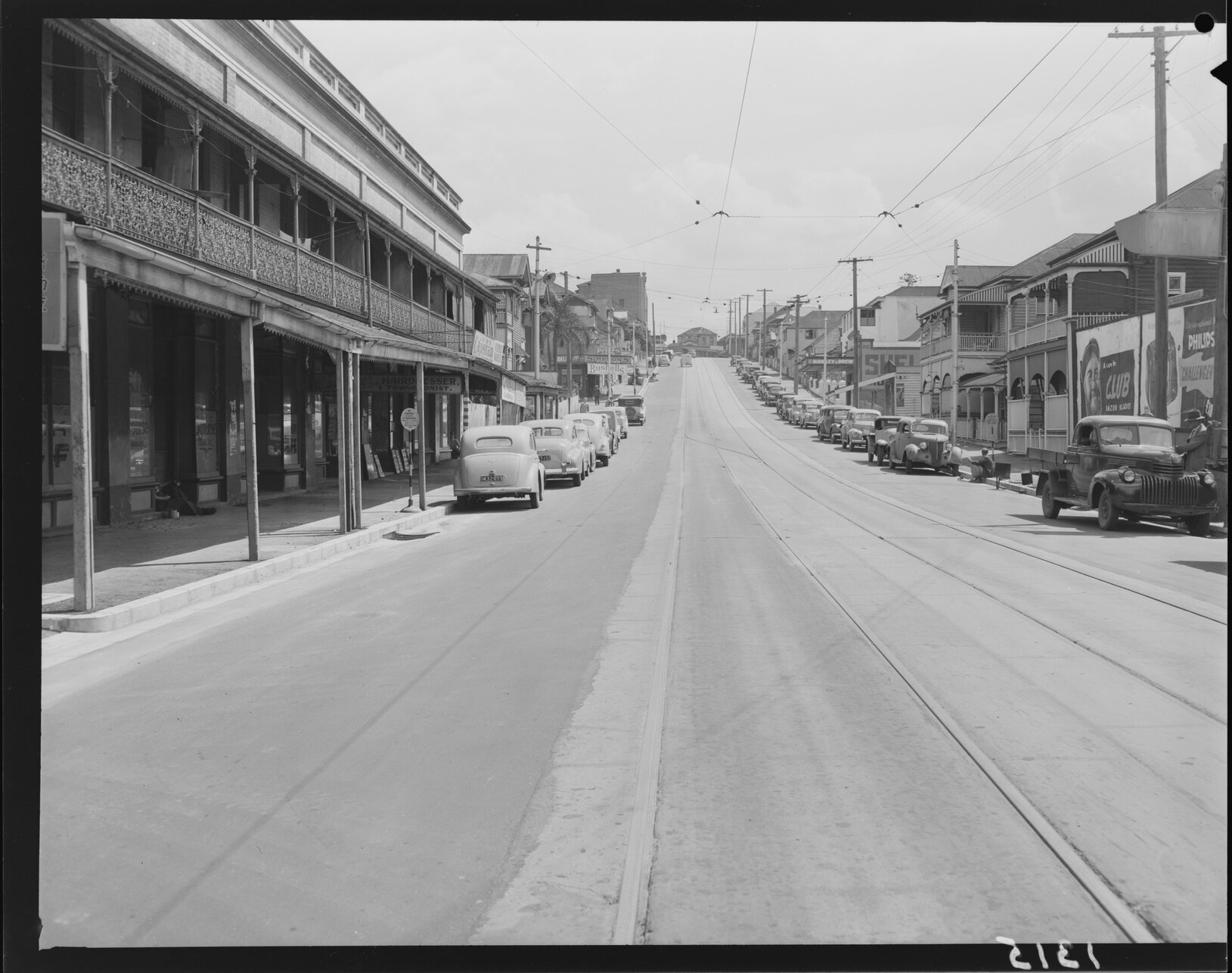 Tramlines and shopfronts, with parked cars, up Wharf Street, Brisbane - 1950