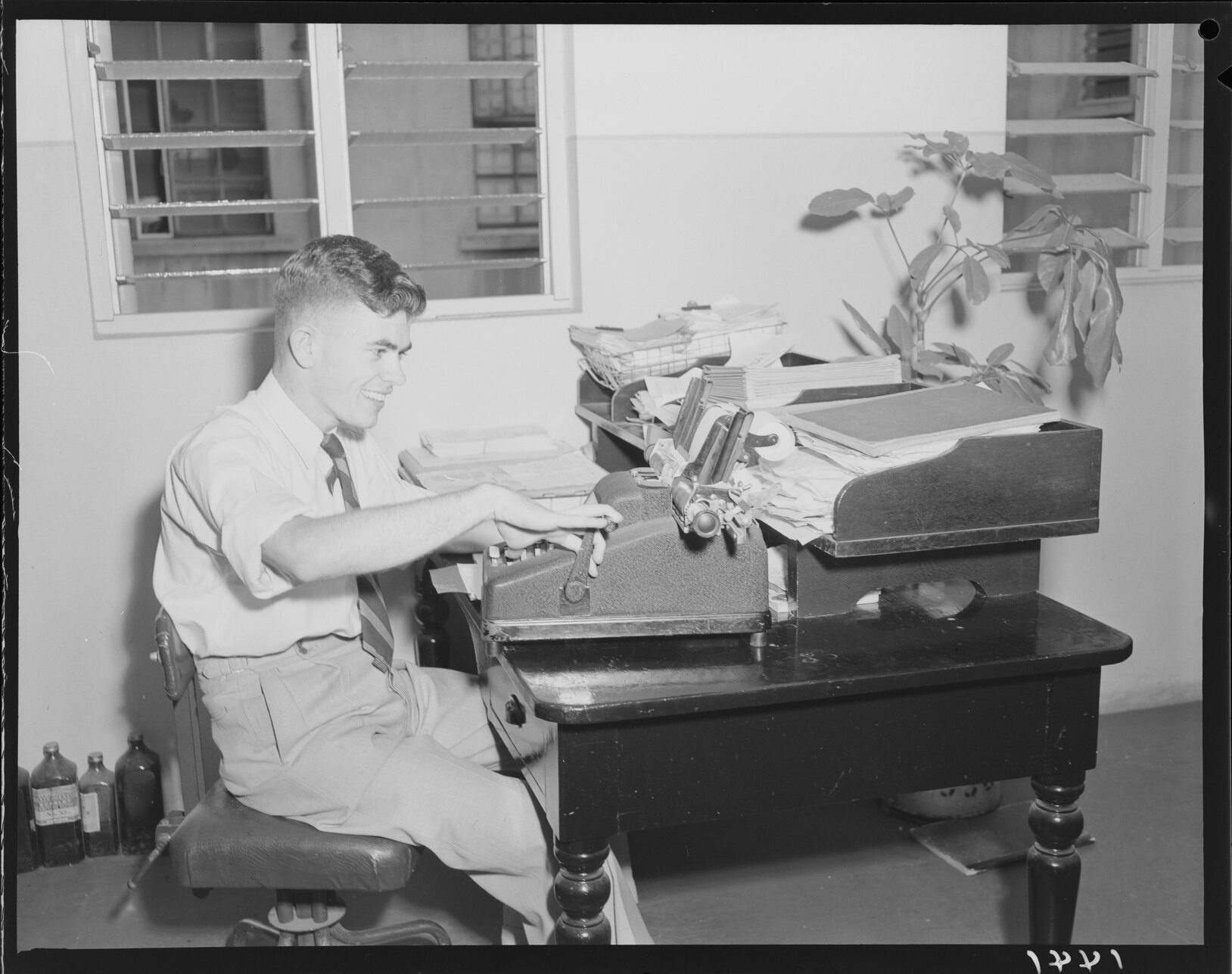 Young man working at City Hall with adding machine - 1950