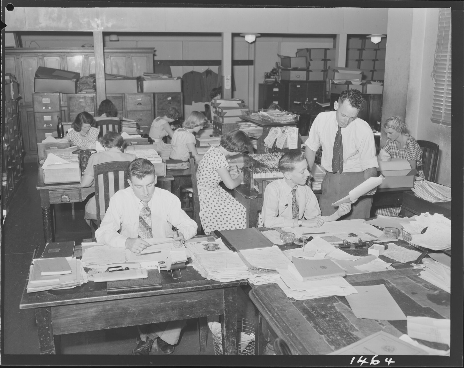 Women and men working at City Hall with paperwork and card files - 1950