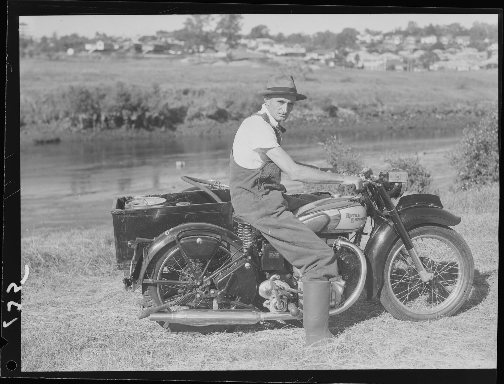 Man sitting on Royal Enfield motorcycle with mosquito spraying equipment in side car - 1949 