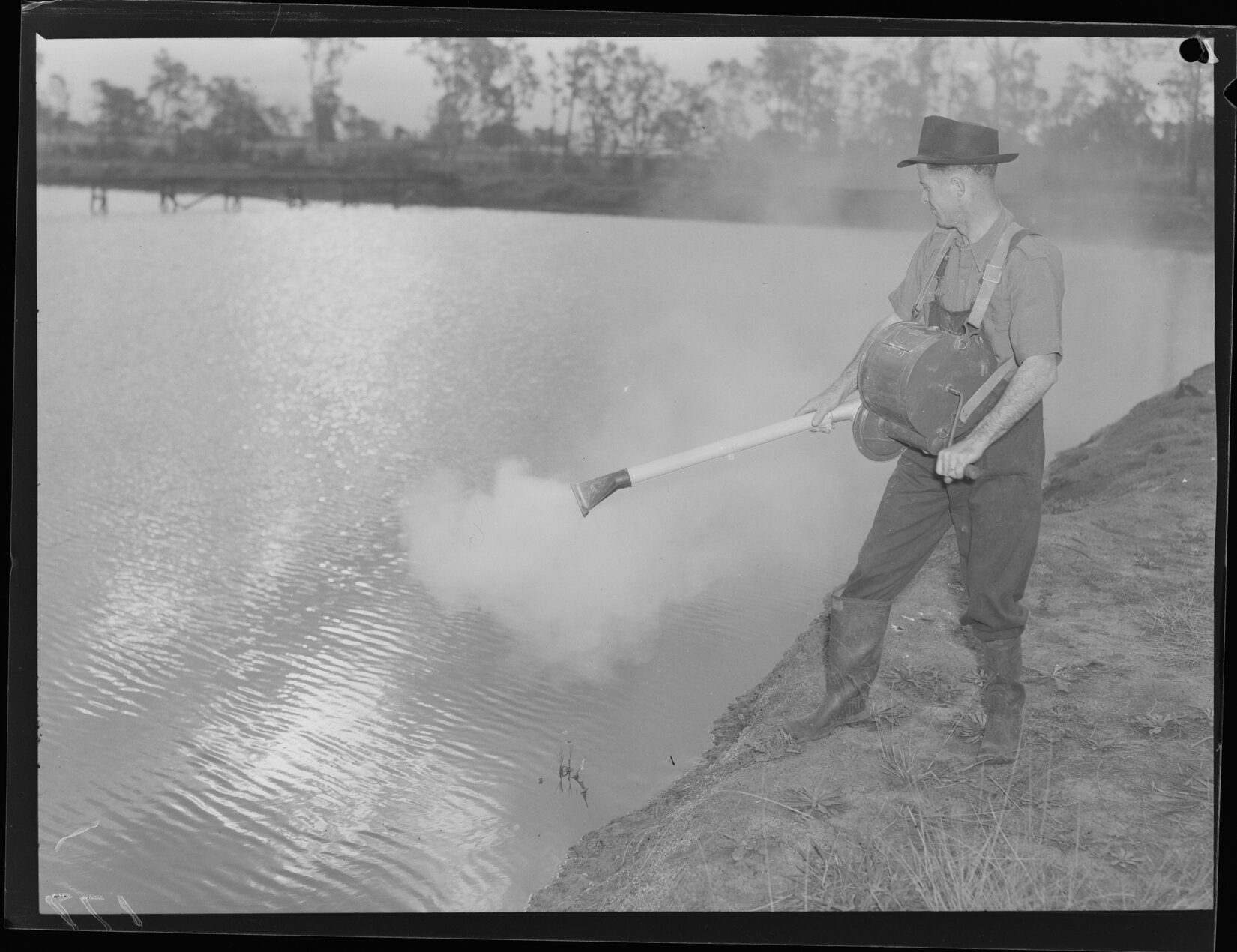 Man turning crank on chest mounted DDT equipment for mosquito spraying at Banyo - 1949