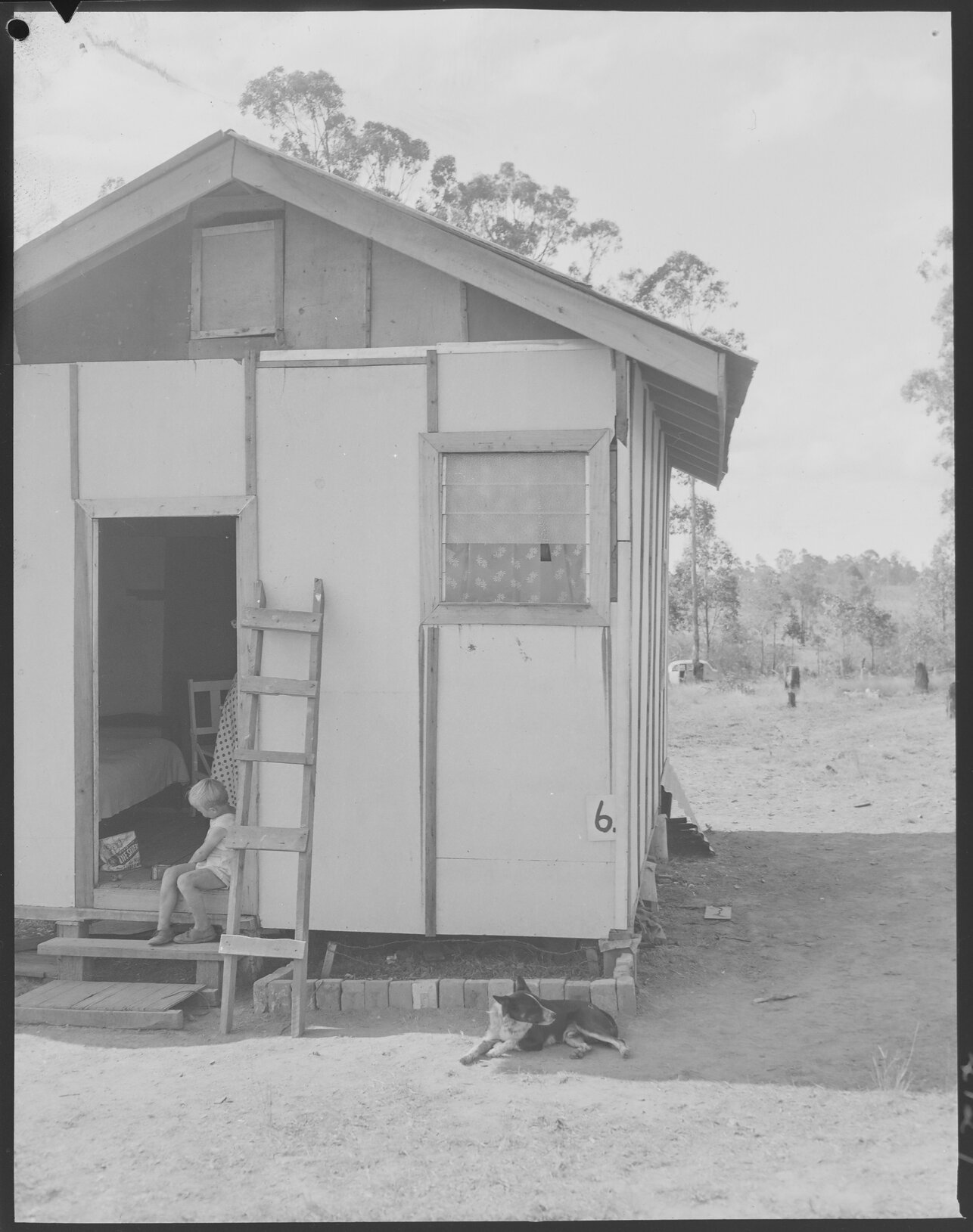 Temporary housing, child with bag of Lifesavers, Coopers Plains - 1953