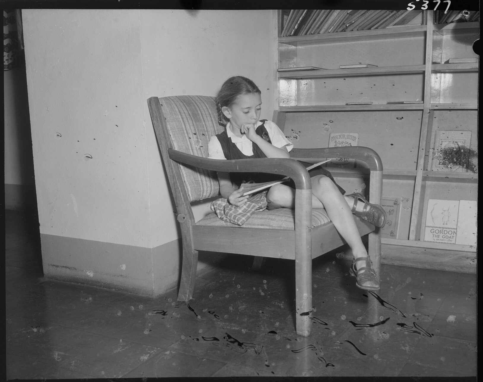 Young schoolgirl in a chair, reading a book, South Brisbane Children's Library - 1954