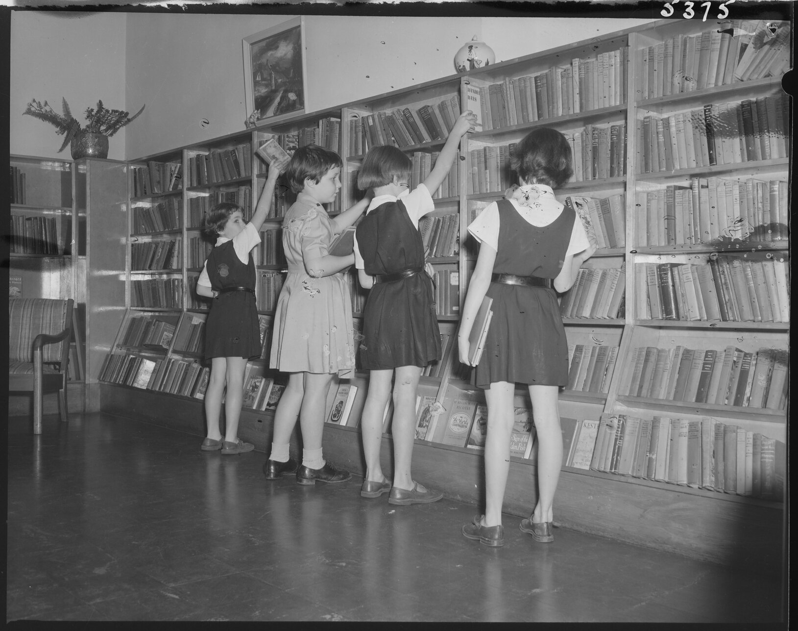 Young schoolgirls looking for books, South Brisbane Children's Library - 1954