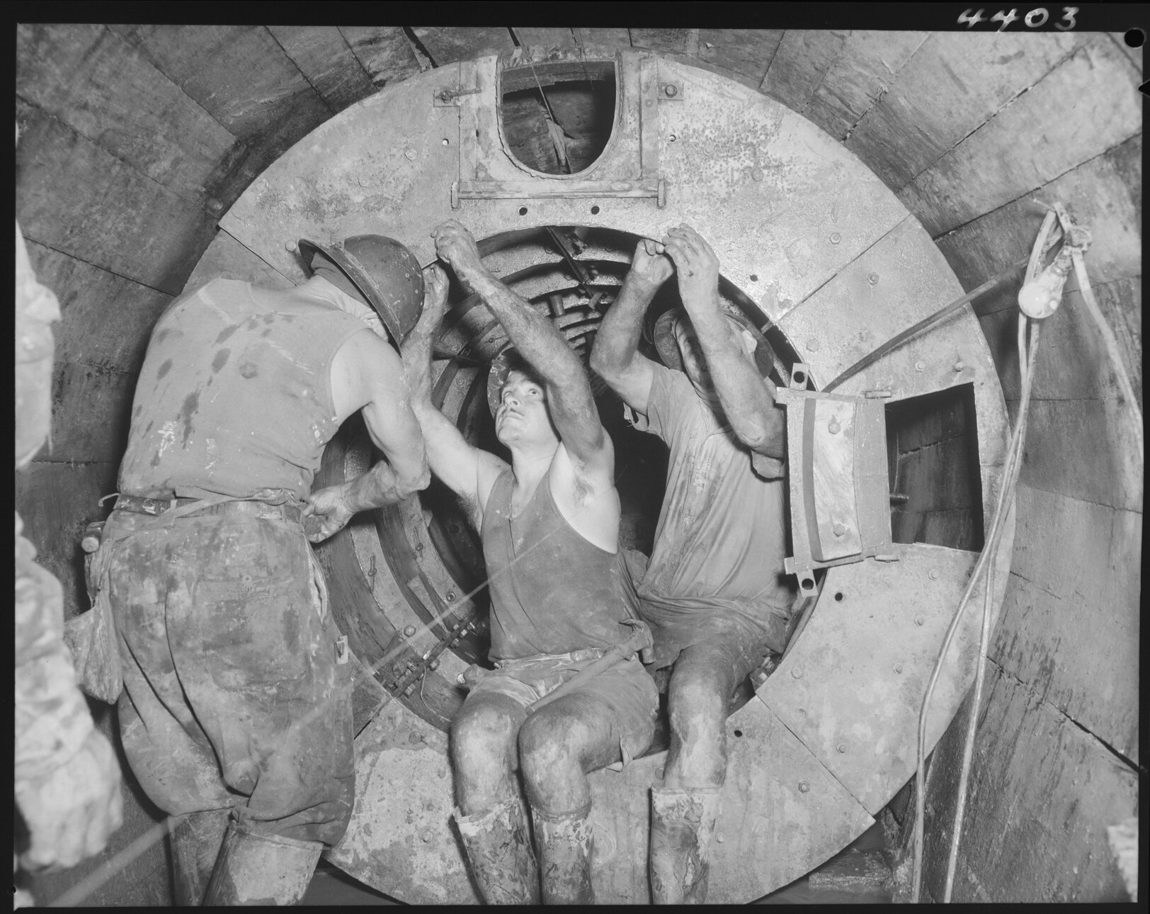 North Kedron Brook sewer concrete framework with three men fixing bolts - 1953
