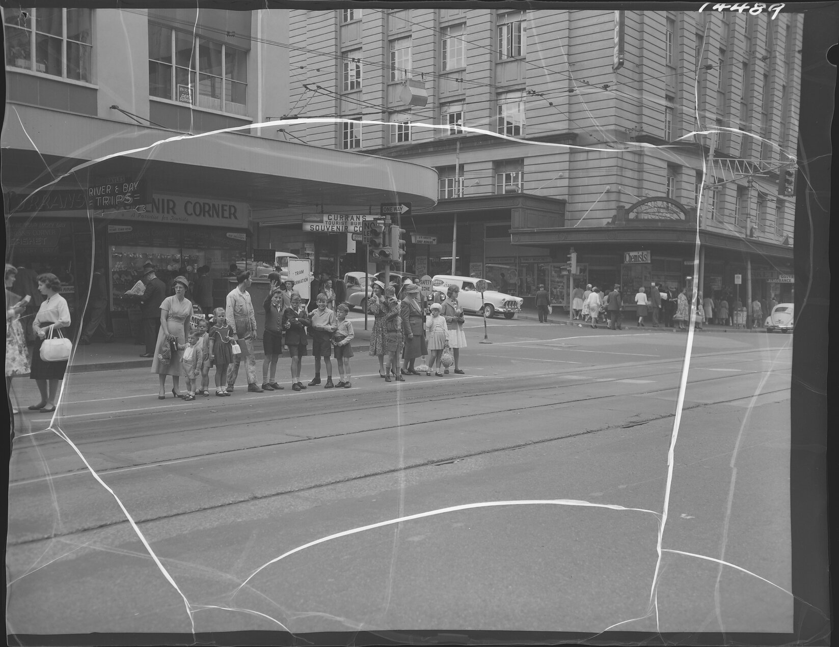 Young families waiting for a tram at the corner of Edward and Adelaide Street, boys making faces at the camera, Brisbane City - 1960