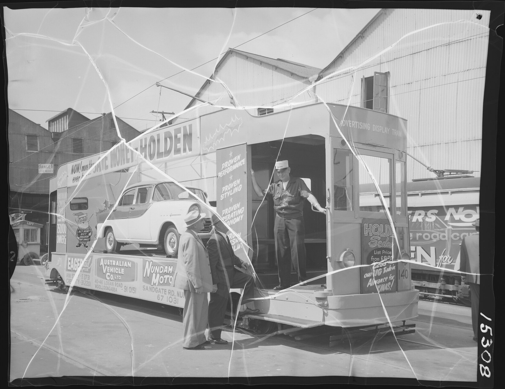Tram driver on advertising Tram No. 140, with Christmas ads for Holden cars at Nundah Motors, Eagers Retail Pty Ltd, and the Australian Vehicle Co Ltd - 1960