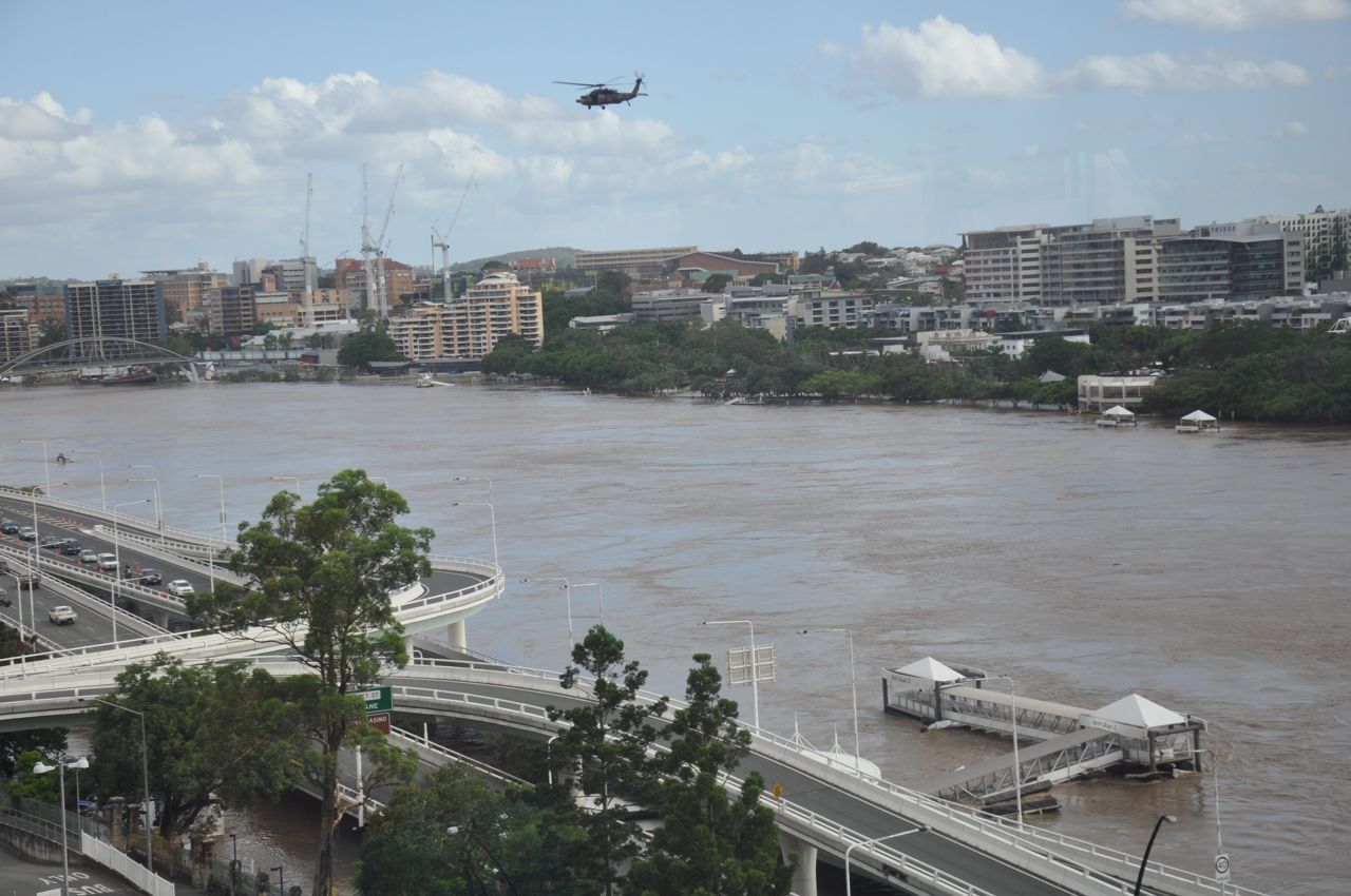 Military helicopter flies over Brisbane River flooding near North Quay ferry terminal, looking towards Kangaroo Point - 2011