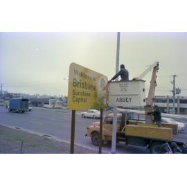 Council worker installing Welcome to Brisbane - Sunshine Capital sign in Underwood, Logan - 1980