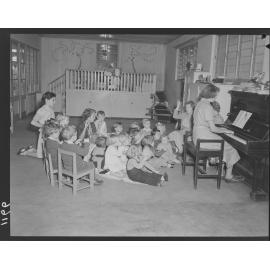 Teachers and children at piano at Kindercraft Civic Nursery (childcare) City Hall - 1950