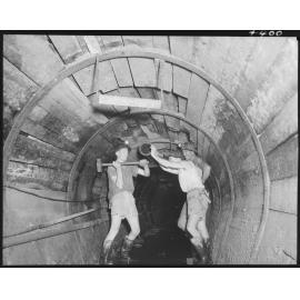 North Kedron Brook sewer concrete framework with three men swinging a hammer - 1953