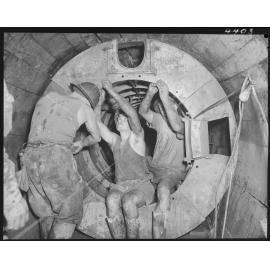 North Kedron Brook sewer concrete framework with three men fixing bolts - 1953