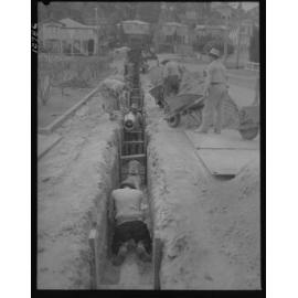 Workmen laying pipe for the Taringa to Tarragindi water main, possibly in Taringa, Tarragindi, Moorooka or Yeronga - 1959